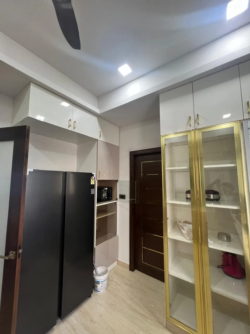 Fitted pantry storage with overhead cupboards and a glass-front cabinet